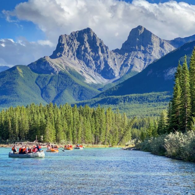 An orange raft on the river with a mountain in the background.