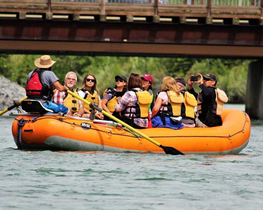 People in an orange raft with a bridge in the background