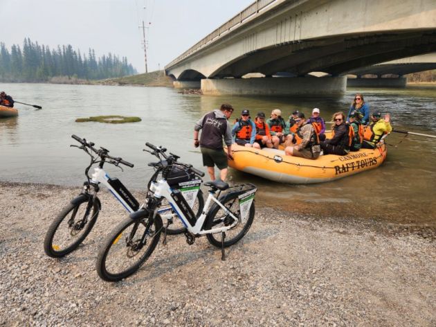 The Canmore Raft Tours vanwith orange rafts in the background.