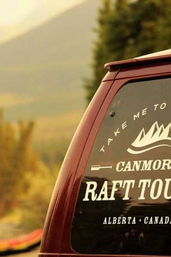 The Canmore Raft Tours vanwith orange rafts in the background.