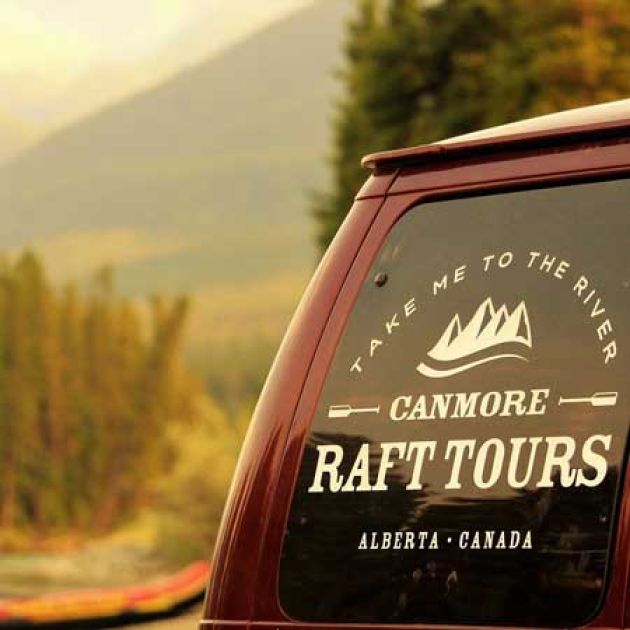 The Canmore Raft Tours vanwith orange rafts in the background.