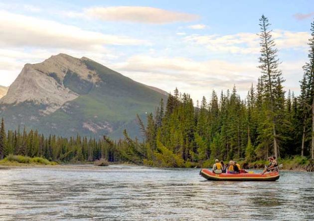 An orange raft on the river with a mountain in the background.